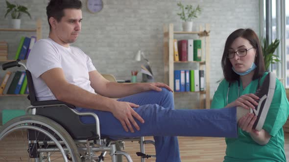 Close Up of the Doctor Examines the Leg of a Disabled Person in a Wheelchair