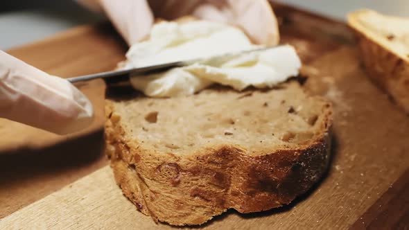 Person Spreads Tasty Cream Cheese on Rye Bread on Table