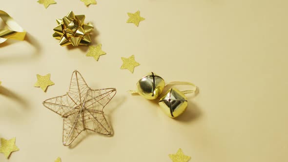 Video of gold christmas decorations with stars on yellow background