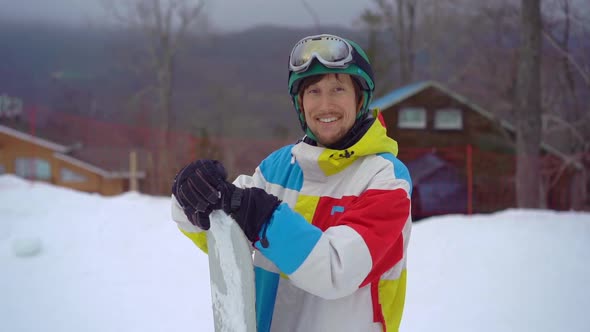 Closeup Shot of a Young Man Wearing a Helmet with a Snowboard in a Mountain Resort Activities Park