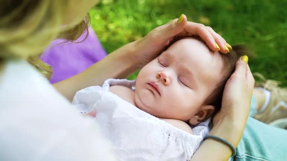 Sweet Baby Girl Sleeping on Lap of Caring Mother Outside