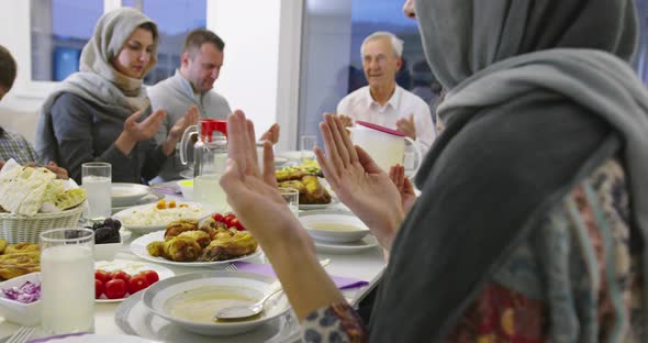 Modern Multiethnic Muslim Family Praying Before Having Iftar Dinner Together During a Ramadan Feast