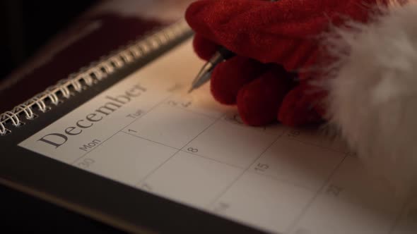 Santa writing in calendar at Christmas close up panning shot