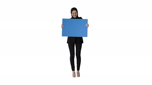 Smiling Arab Woman in Hijab Holding Blank Blue Poster and Looking at It on White Background