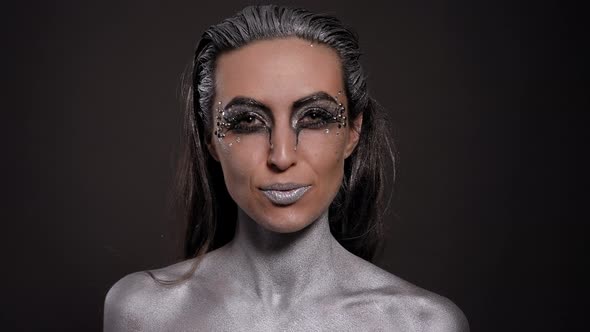 Portrait of a Female Model with Silver Skin and Makeup on a Black Background