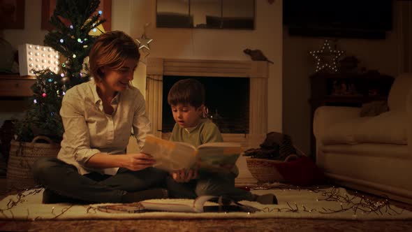 Mother reading book with son on Christmas eve