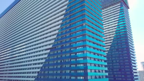 shot of reflections of sun, clouds and sky on glass windows of city skyscraper.