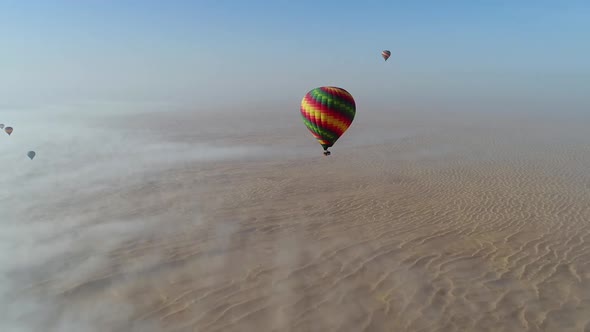 Aerial view of hot-air-balloon flying in the clouds on desert in Dubai, U.A.E.