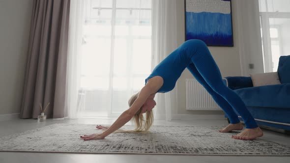 A Woman Trains at Home on the Carpet in the Apartment