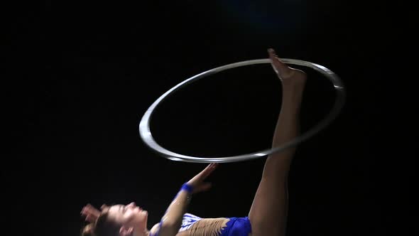 Girl Gymnast Turns the Metal Hoop on the Arm Then on the Leg. Black Background. Slow Motion
