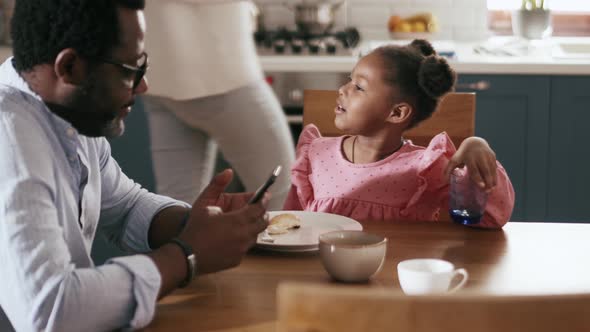 Mother clearing dishes and talking with daughter