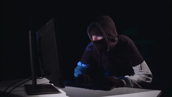 Spy Hacking Computer Sitting in a Dark Room. Black Background