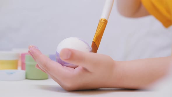 A Little Kid Learns to Paint Eggs with a Brush