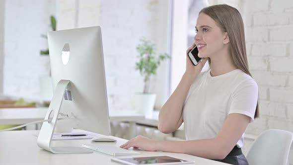 Happy Young Woman Talking on Smart Phone in Office