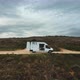 Drone shot zooming out to coastal landscape featuring two man and a van - VideoHive Item for Sale