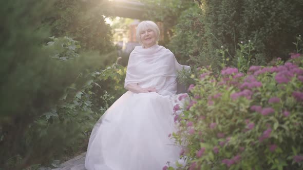 Happy Senior Bride Sitting on Chair in Sunshine Hanging Shawl on Shoulder in Slow Motion