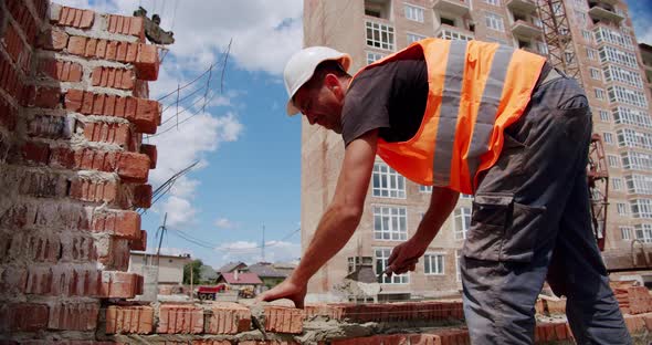 A Construction Worker Puts Mortar and Starts Laying Bricks To Build a House
