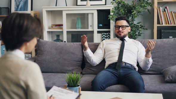 Businessman Talking To Therapist During Session in Office of Modern Clinic