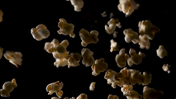 Big pile of popcorn falls in slow motion on the camera in a studio with a isolated black background.