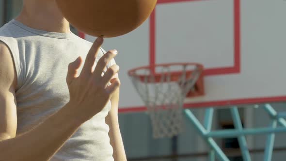 Muscular caucasian athlete masterfully spinning basketball on his finger, trick