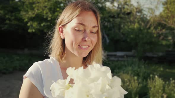 Portrait of a young smiling woman with a bouquet of white irises.