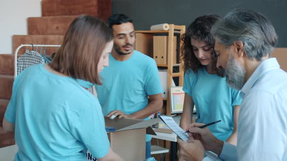 Diverse Group of People Volunteers Packing Boxes with Clothing for Donation Working in Charity