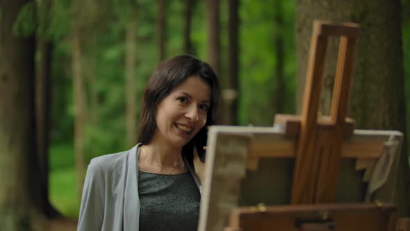 Girl Artist Painting a Picture in the Forest and Talking By Mobile Phone