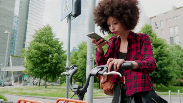Woman with city bike looking at smartphone, smiling