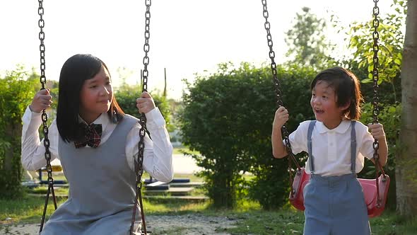 Asian Girl And Her Brother Playing Swing Together In The Park Slow Motion