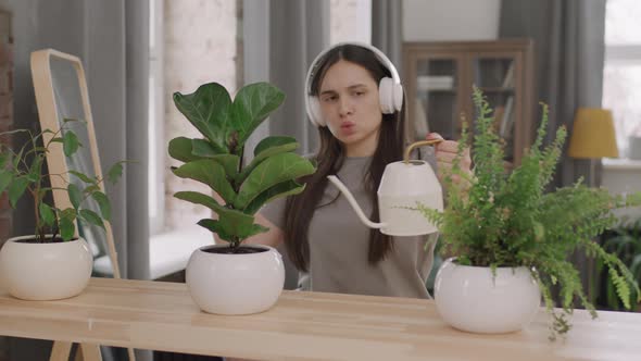 Woman in Headphones Listening to Music and Water Plants