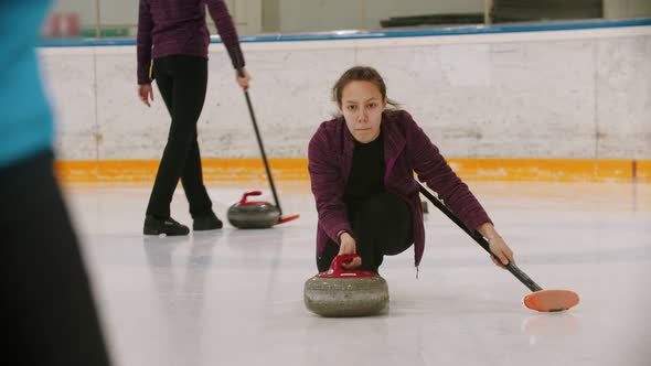 Curling - a Woman Skating on the Ice Field and Leading a Granite Stone