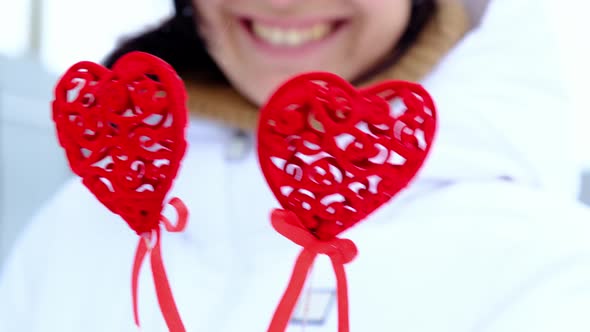 Happy woman with heart-shaped decor like glasses at eyes outdoor in winter