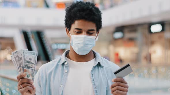 African American Man Guy Male Winner Wears Medical Face Mask Holds Bank Card and Dollars Money in