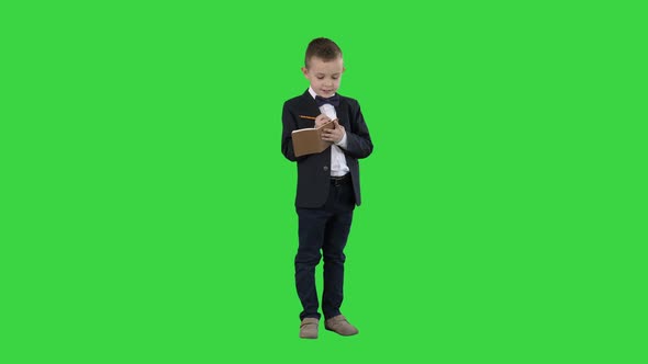 Boy in a Formal Clothes Writing in Check List or Notebook on a Green Screen, Chroma Key