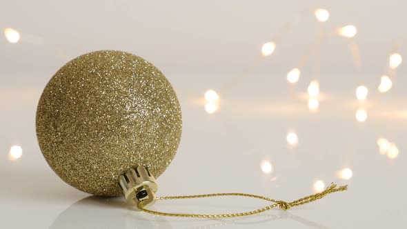 Golden color Christmas ornament and fairy lights 4K 2160p 30fps UltraHD footage - Tilting on bauble 