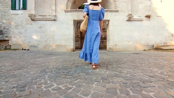 Young woman in a blue dress walking on the street in the city. Split, Croatia