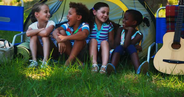 Kids sitting outside tent at campsite