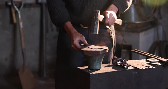 Bladesmith finishing blade with hammer on an anvil