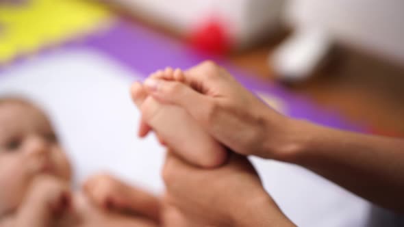 Woman Massaging the Foot of a Lying Baby