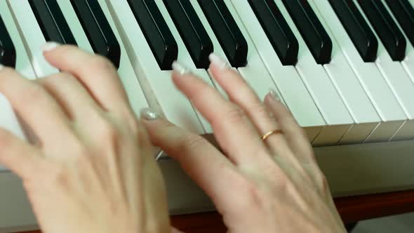 Close-up of female and children's hands playing the piano