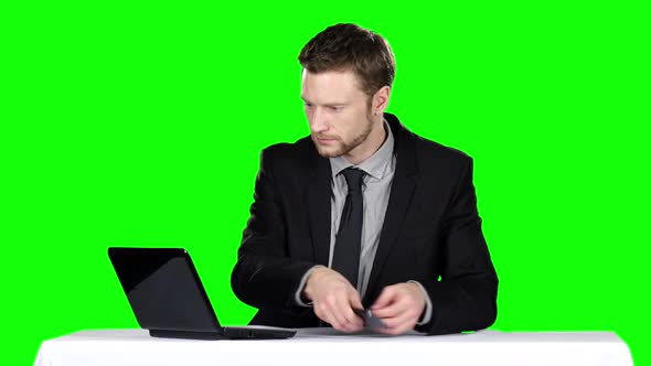 Businessman Sitting at a Desk and Using Notebook and Calling on the Phone. Green Screen