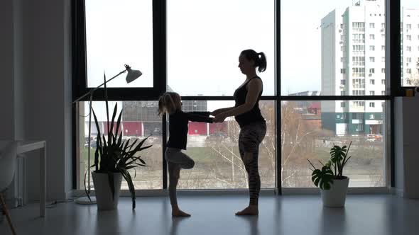 Little Girl with Mom Doing Yoga Exercises Indoors