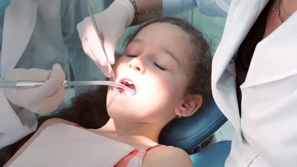 Dentist in the Dental Office Woman Dentist Treating Teeth to Little Girl Child Patient in Clinic