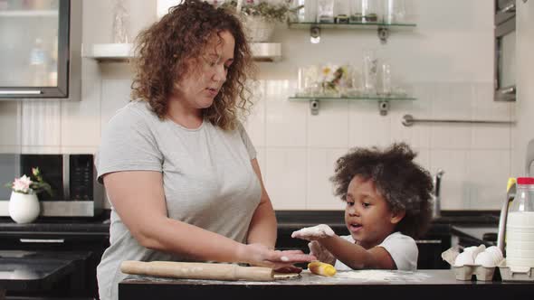 Black Little Girl with Her Mother Making Dough