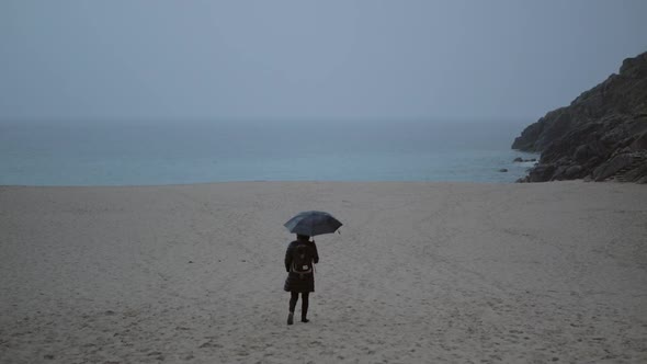 A Lonely Woman with an Umbrella Walks Along the Beach To the Seashore