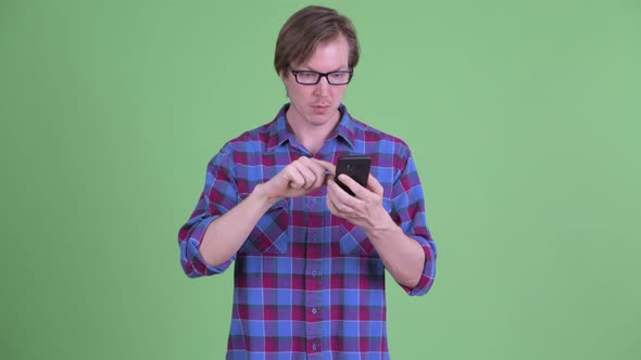 Young Handsome Hipster Man Using Phone and Looking Shocked