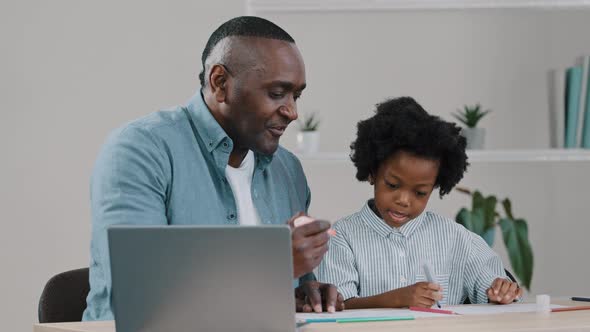 Mature African American Grandfather Helps Granddaughter with Homework Little Girl Surprised Draws