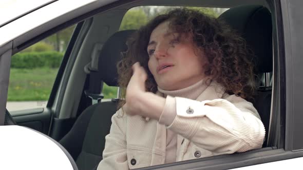 Sad Middleaged Woman is Sitting in Thought Behind the Wheel of Her Car