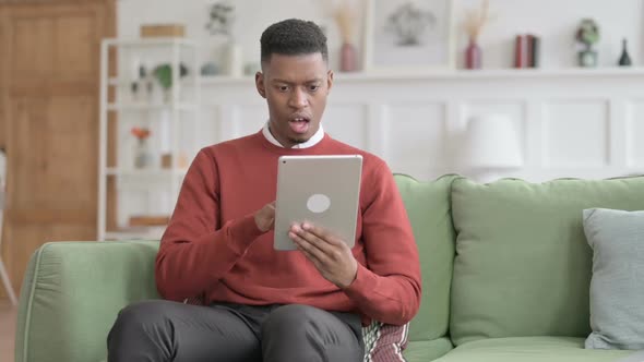 African Man having Loss on Tablet on Sofa