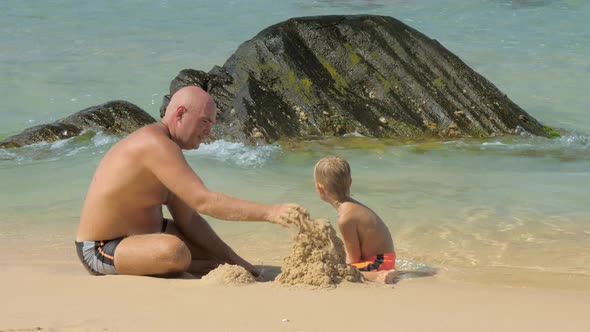 Boy and Father Look at Sand Tower Destroyed By Sea Waves